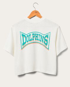 Step up your Dolphins game-day look with the Women's Dolphins Mock Neck Crop Tee! This NFL-licensed apparel combines Miami Dolphins pride with a sleek mock neck design. With its flattering crop cut and sporty logo, you'll stand out in style while cheering for your team. Perfect for fashion-forward football fans! Shop the rest of our Women's NFL Collection HERE. Nfl T Shirts, Food Clothes, Mock Neckline, Miami Dolphins, Football Fans, Shirt Sale, Crop Tee, Neck Designs, Step Up