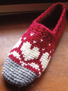 a knitted slipper sitting on top of a wooden floor