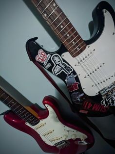 two guitars with stickers on them sitting next to each other