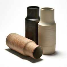 three different vases sitting next to each other on a white surface with one black and one brown