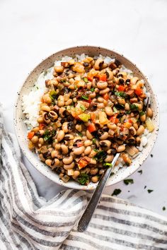 a bowl filled with rice and beans on top of a striped towel next to a spoon