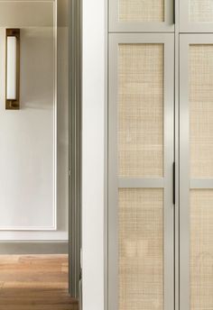 an empty room with white walls and wooden flooring next to a tall cabinet in the corner