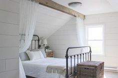 a bedroom with white walls and wood flooring has a metal bed frame in the corner