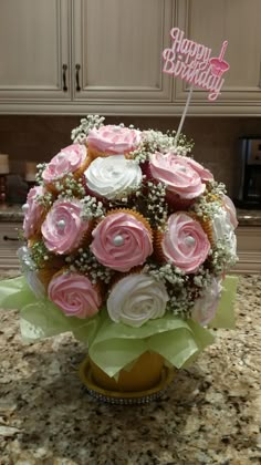 a cupcake bouquet with pink and white frosting in a vase on a kitchen counter