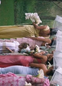 several women laying on the ground with umbrellas