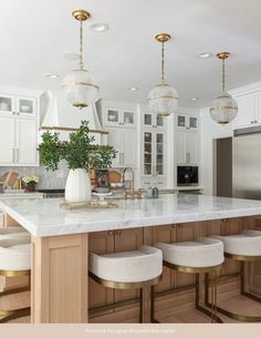 a kitchen island with stools and lights hanging from it's ceiling over the counter