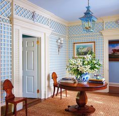 a room with blue and white wallpaper, two chairs and a table in it