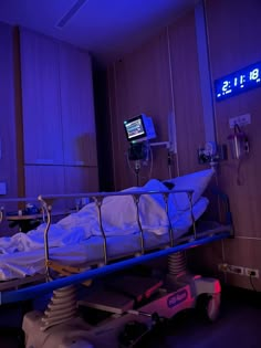 an empty hospital bed in a room with blue lights