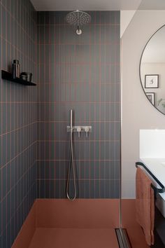 a bathroom with a walk in shower sitting next to a white sink under a round mirror