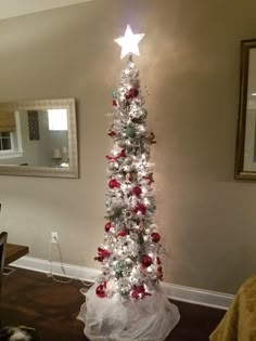 a white christmas tree with red, green and silver ornaments in the shape of a star