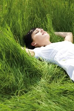 a woman laying in the grass with her eyes closed