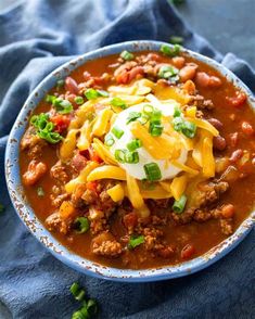 a bowl filled with chili and cheese on top of a blue towel