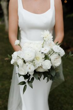 a bride holding a bouquet of white flowers