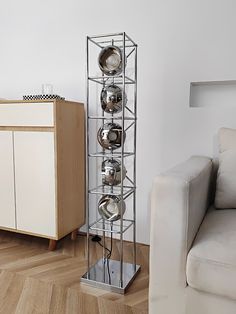 a metal rack holding pots and pans on top of a wooden floor next to a white couch