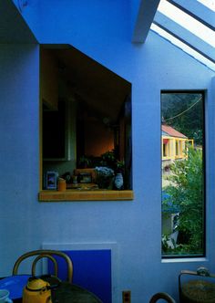 an open window in a blue room with a table and chairs next to the window