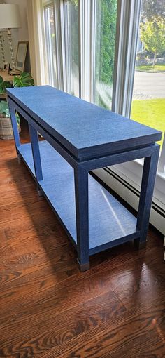 a blue table sitting on top of a hard wood floor next to a large window