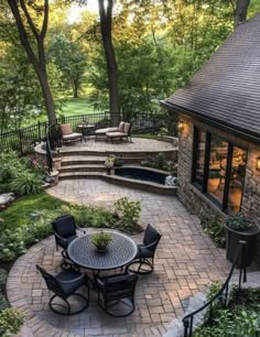 an outdoor patio with chairs, table and fire pit in the middle of some trees