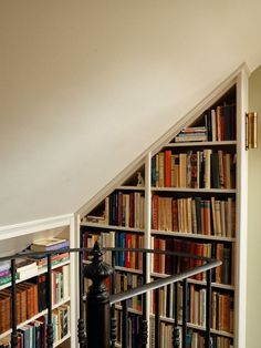 a bookshelf filled with lots of books under a slanted ceiling next to a fire hydrant