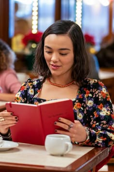 a woman sitting at a table reading a book