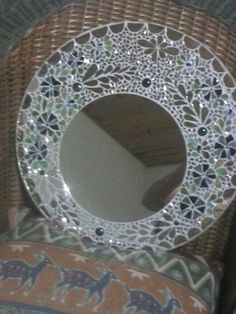 a mirror sitting on top of a wicker chair next to a cushion and pillow