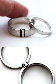 two silver rings with black lettering on them and one has a finger in the middle