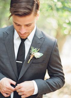 a man wearing a suit and tie with a boutonniere on his lapel