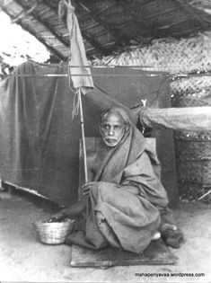 an old black and white photo of a woman sitting on the ground with a basket