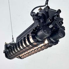 an industrial light fixture suspended in the air with wires and lights attached to it's sides