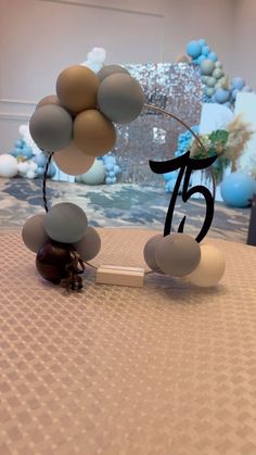 a table topped with balloons and a cake topper in the shape of number 75