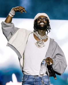 a man with dreadlocks and a white shirt holding a water bottle in his right hand