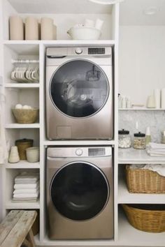 a washer and dryer in a small room with white shelves on the wall