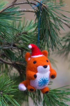 an ornament hanging from a pine tree with a red and white bear on it