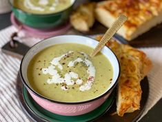 there is a bowl of soup and some bread on the table next to each other