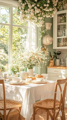 a dining room table with flowers hanging from it's ceiling and plates on the table