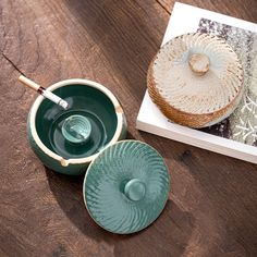 two green bowls and a book on a wooden table with a brush in the bowl