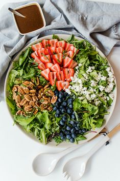 a salad with strawberries, blueberries, pecans and feta cheese on it