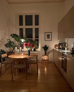 a dining room table and chairs in front of a window with plants on the windowsill