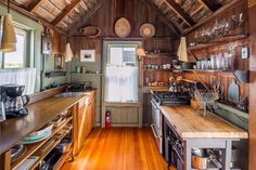 a kitchen with wood floors and wooden walls, along with lots of hanging baskets on the ceiling