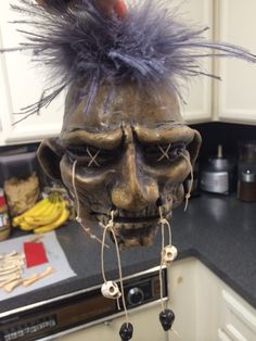 a creepy mask hanging from the side of a kitchen counter with hair on it's head