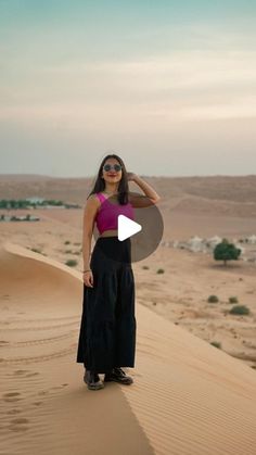 a woman standing on top of a sand dune