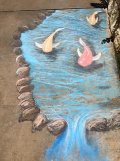 there is a chalk drawing on the ground with koi fish swimming in water and rocks