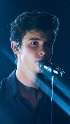 a young man singing into a microphone on stage