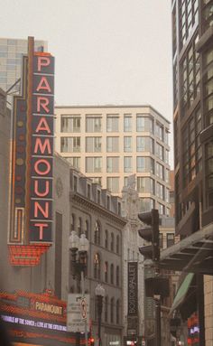 a city street filled with tall buildings next to traffic lights and people walking on the sidewalk