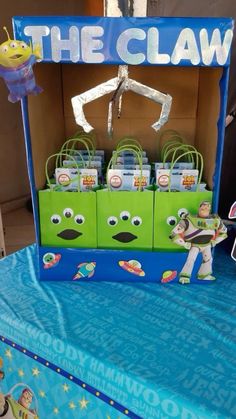 the claw is set up on top of a blue table cloth with green bags in front of it