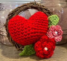 a crocheted heart sitting on top of a wooden table next to a flower