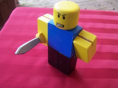 a lego man holding a knife on top of a pink tableclothed area with red and white stripes