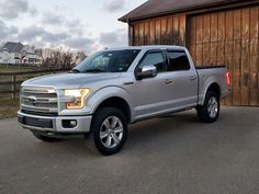 a silver truck parked in front of a barn