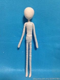 a small white doll standing in front of a blue background