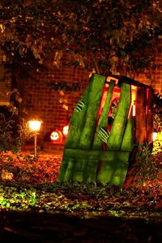 a large piece of green art sitting in the middle of a park at night with lights on it