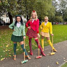 three women dressed in costumes are posing for the camera while holding brooms and standing next to each other